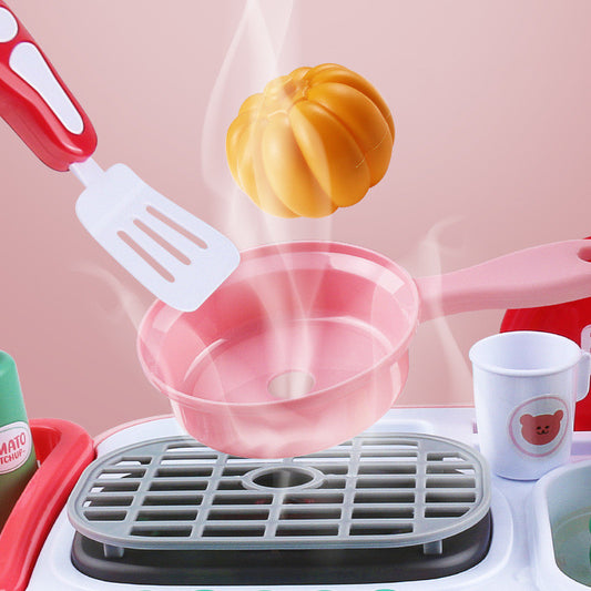 Kids' interactive toy kitchen with pink pan, spatula, and steaming pumpkin.