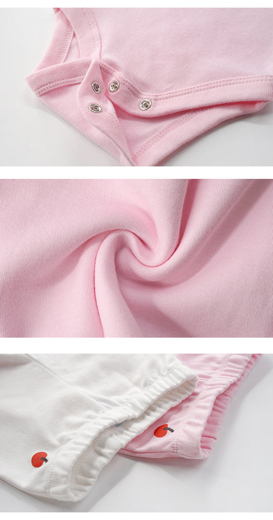 Close-up of soft pink cotton baby bodysuit snaps, fabric texture, and white/pink bottoms with apple embroidery.
