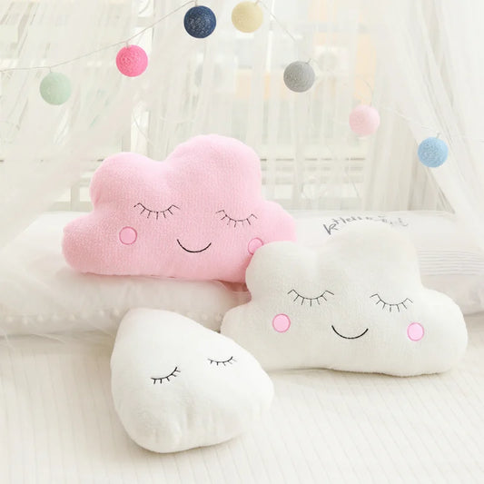 Soft pink cloud, white cloud, and white raindrop plush pillows with sleepy embroidered faces for nursery decor.