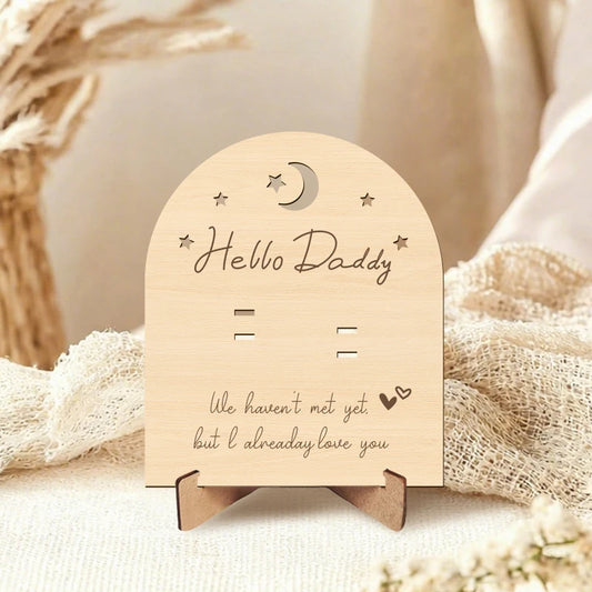 Arched natural wood pregnancy announcement sign with "Hello Daddy" and "We haven't met yet but I already love you" text.