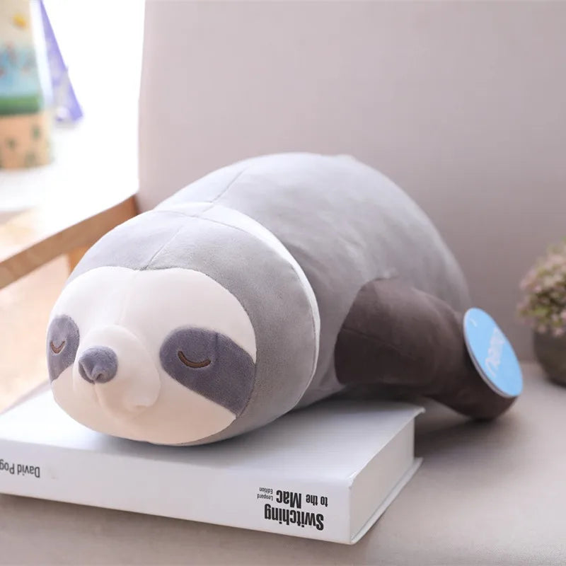 Soft gray and brown plush sloth toy, 65-100cm, lying on a white book, with a blue tag.