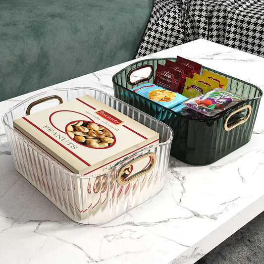 Clear and green ribbed PET storage bins with gold handles, holding snacks on a marble table.