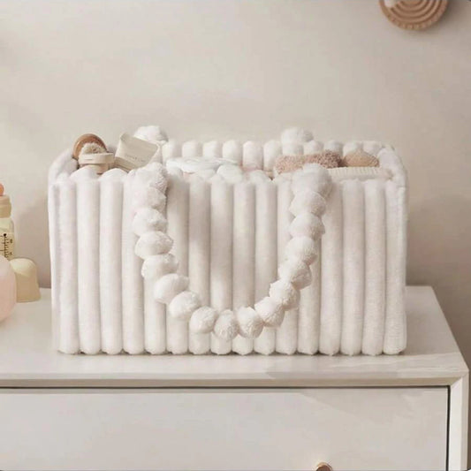 White flannel diaper caddy with ribbed texture and pom-pom handle, filled with baby essentials.