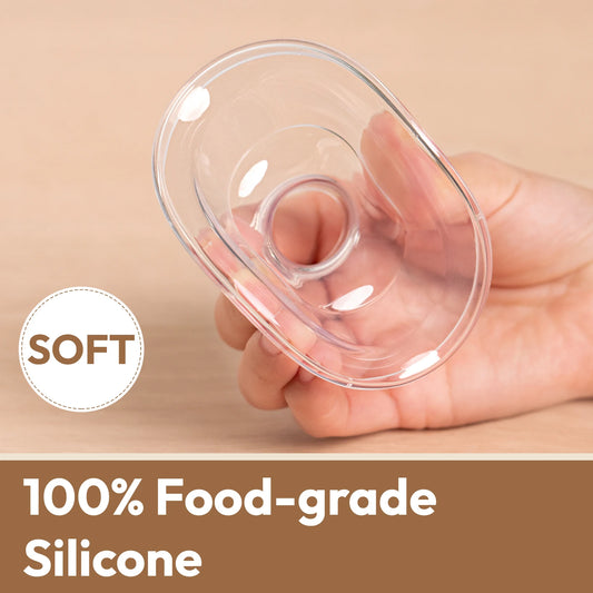 Hand holding a clear, soft, 100% food-grade silicone breast pump flange.