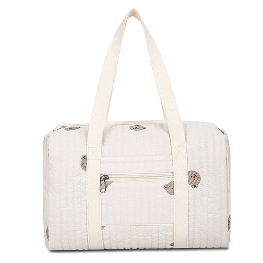 Quilted cream diaper bag with brown bear print, front zipper pocket, and sturdy top handles.