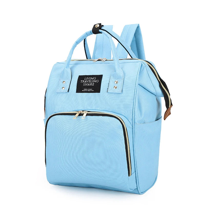 Light blue canvas diaper backpack with multiple zippered pockets and top handles.