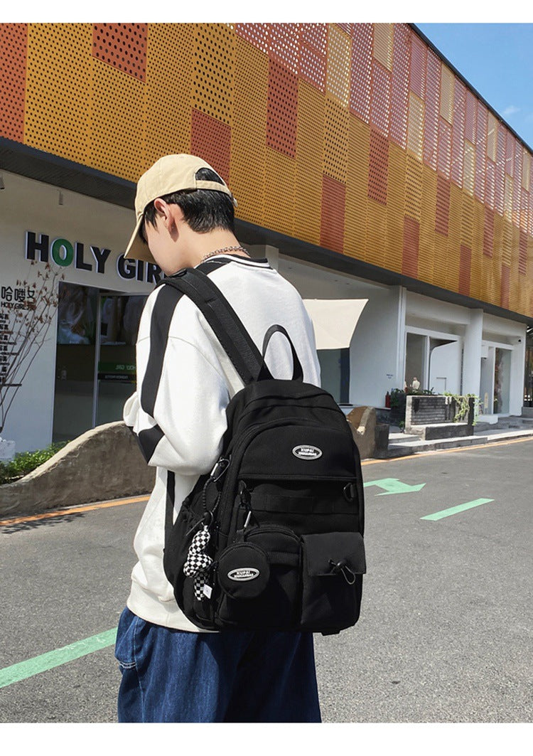 Black nylon student backpack with laptop compartment, multiple pockets, and a checkered charm.