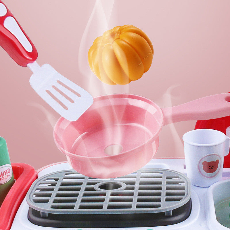 Kids' interactive toy kitchen with pink pan, spatula, and steaming pumpkin.