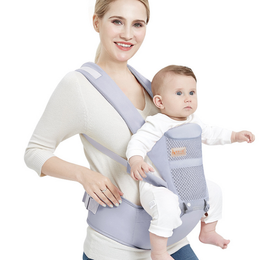 Smiling woman carrying a baby in a gray ergonomic waist stool baby carrier with breathable mesh.