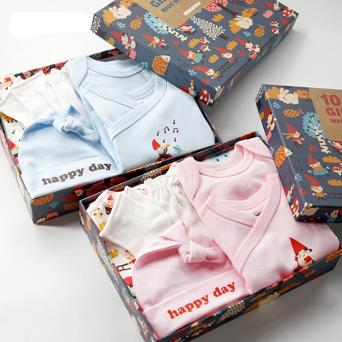 Two open gift boxes with 10-piece cotton baby sets in blue and pink, featuring "happy day" hats.