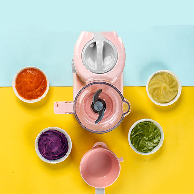 Pink baby food steamer and blender with pureed vegetables in bowls on a yellow and blue background.