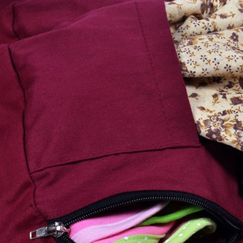 Close-up of a burgundy cotton baby carrier with a zippered pocket holding colorful fabric.