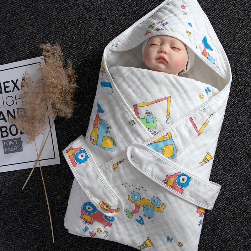 White cotton gauze baby swaddle with colorful construction vehicle print, featuring a hood and adjustable straps.