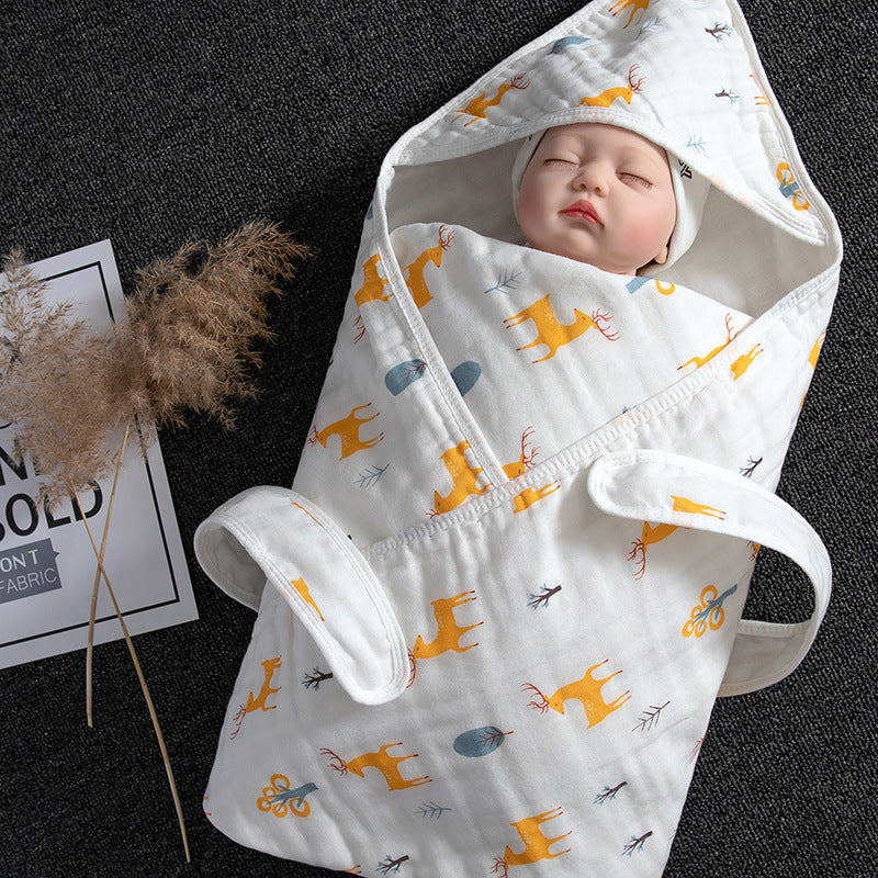 White cotton gauze baby swaddle with yellow deer print, featuring a hood and adjustable straps, wrapped around a doll.
