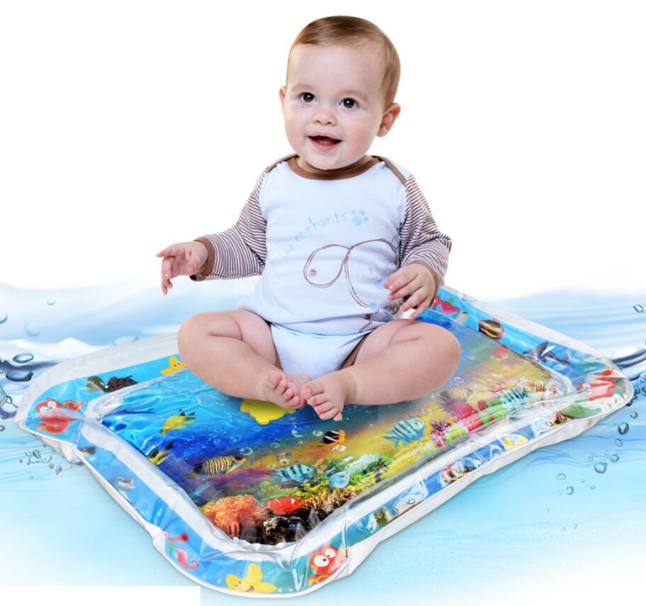 Happy baby on a colorful inflatable water play mat with floating sea creatures, promoting tummy time.