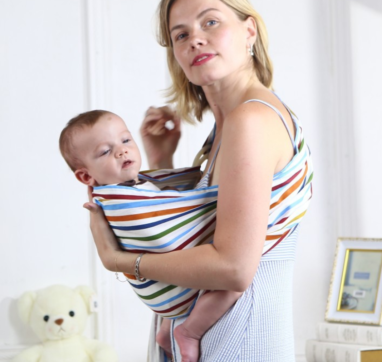 Woman holding baby in a soft, breathable cotton sling carrier with colorful stripes.