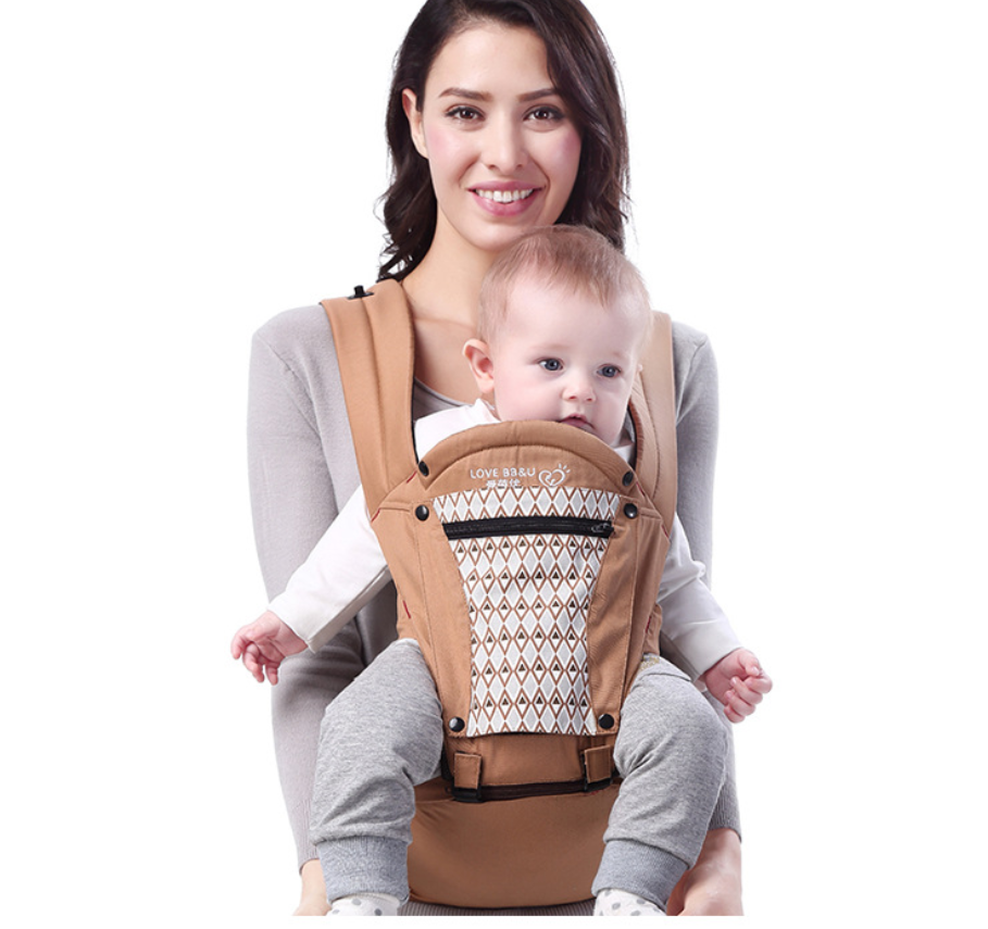 Smiling mother carrying baby in a brown ergonomic cotton baby carrier with patterned front pocket.