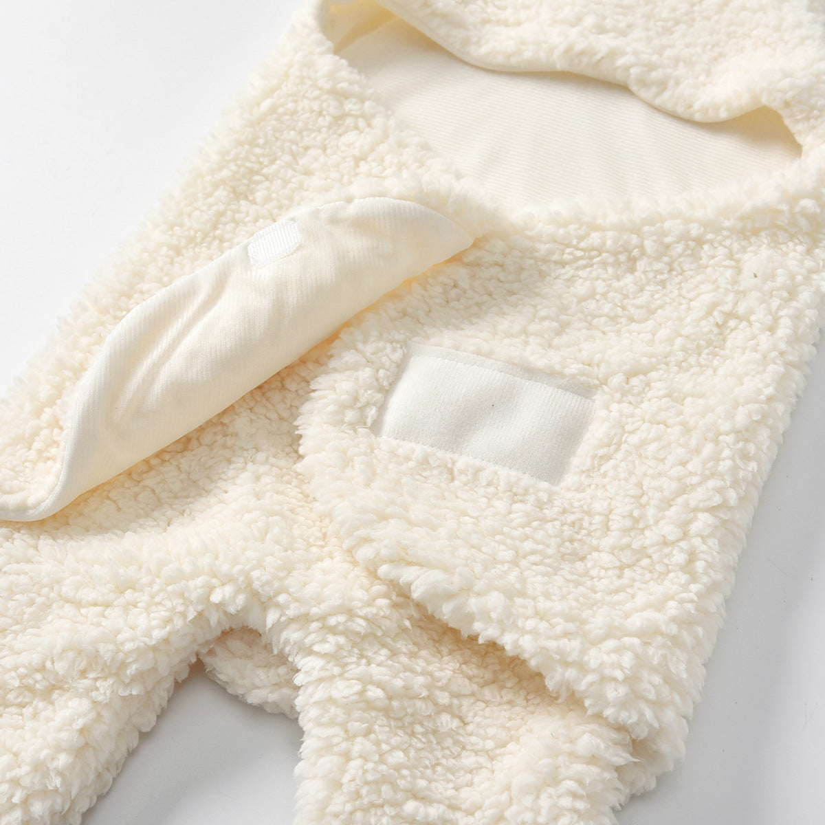 Creamy white fleece baby swaddle blanket with soft texture and velcro closure.