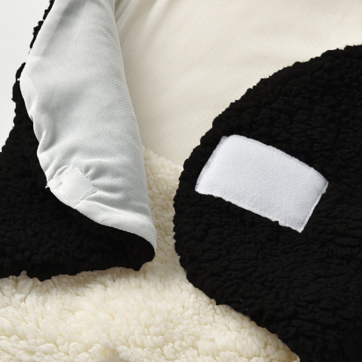 Soft black and white fleece baby swaddle blanket with velcro closure.