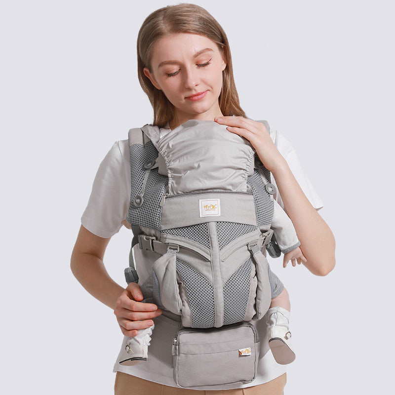 Gray ergonomic cotton baby carrier with breathable mesh, worn front-facing by a woman.