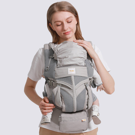 Gray ergonomic cotton baby carrier with breathable mesh, worn front-facing by a woman.