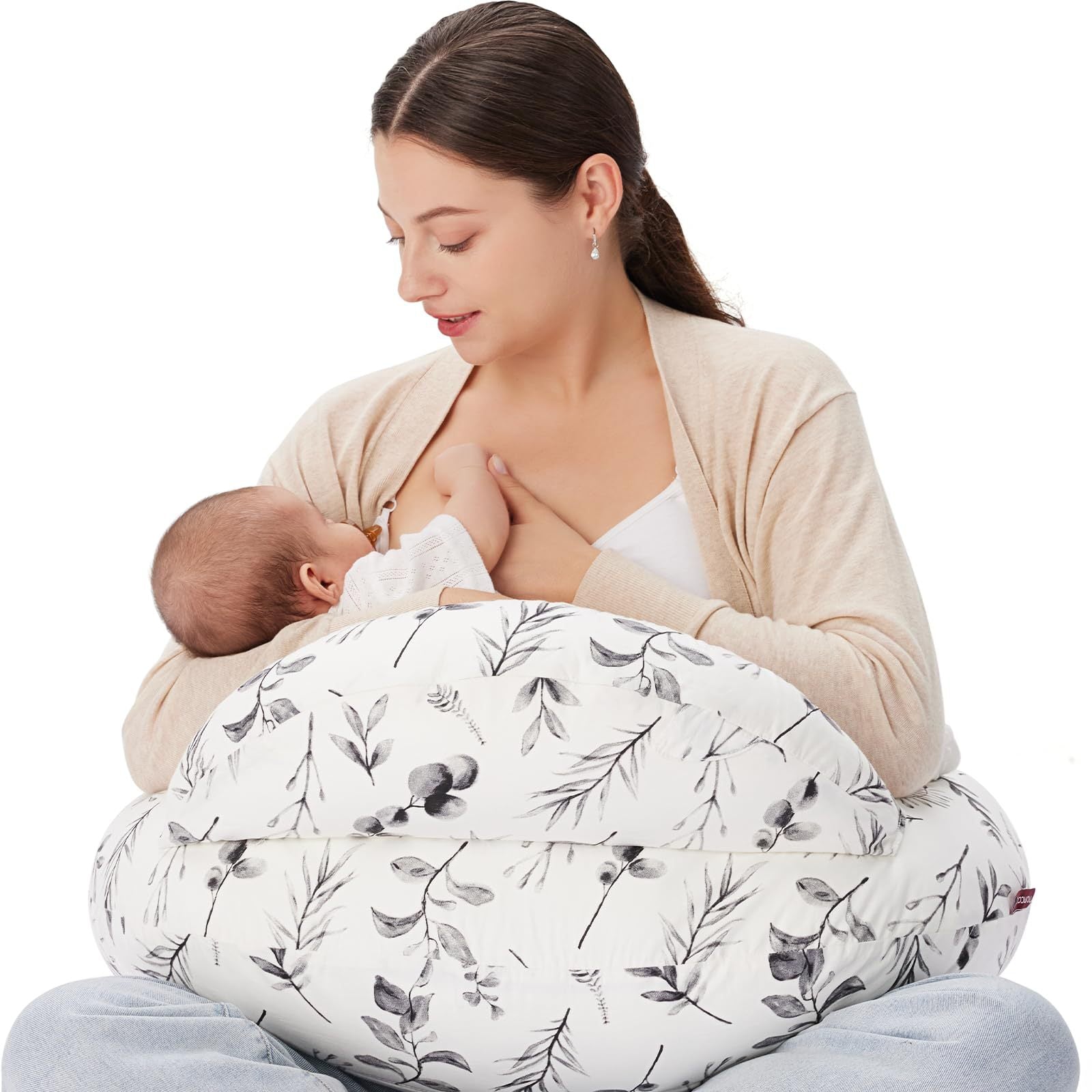 Woman breastfeeding baby using a white nursing pillow with a gray leaf pattern, featuring a removable cover.