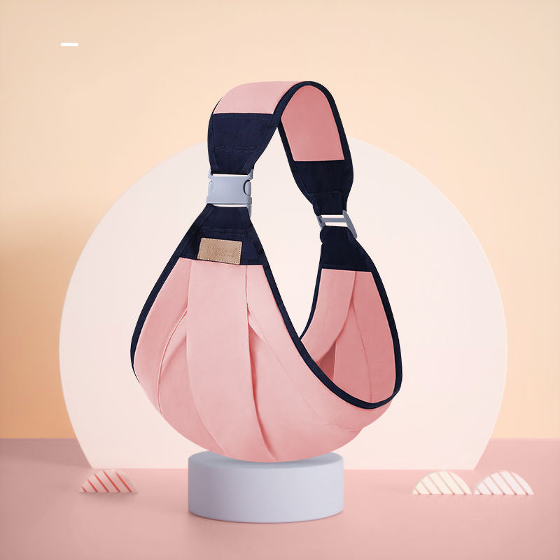 Ergonomic pink and navy baby sling carrier with adjustable strap and buckle, designed for single-shoulder use.