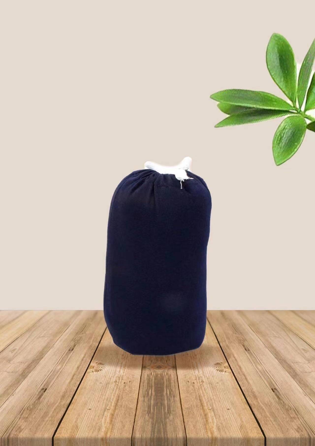 Folded navy blue soft ergonomic baby wrap carrier with white ties on a wooden surface.