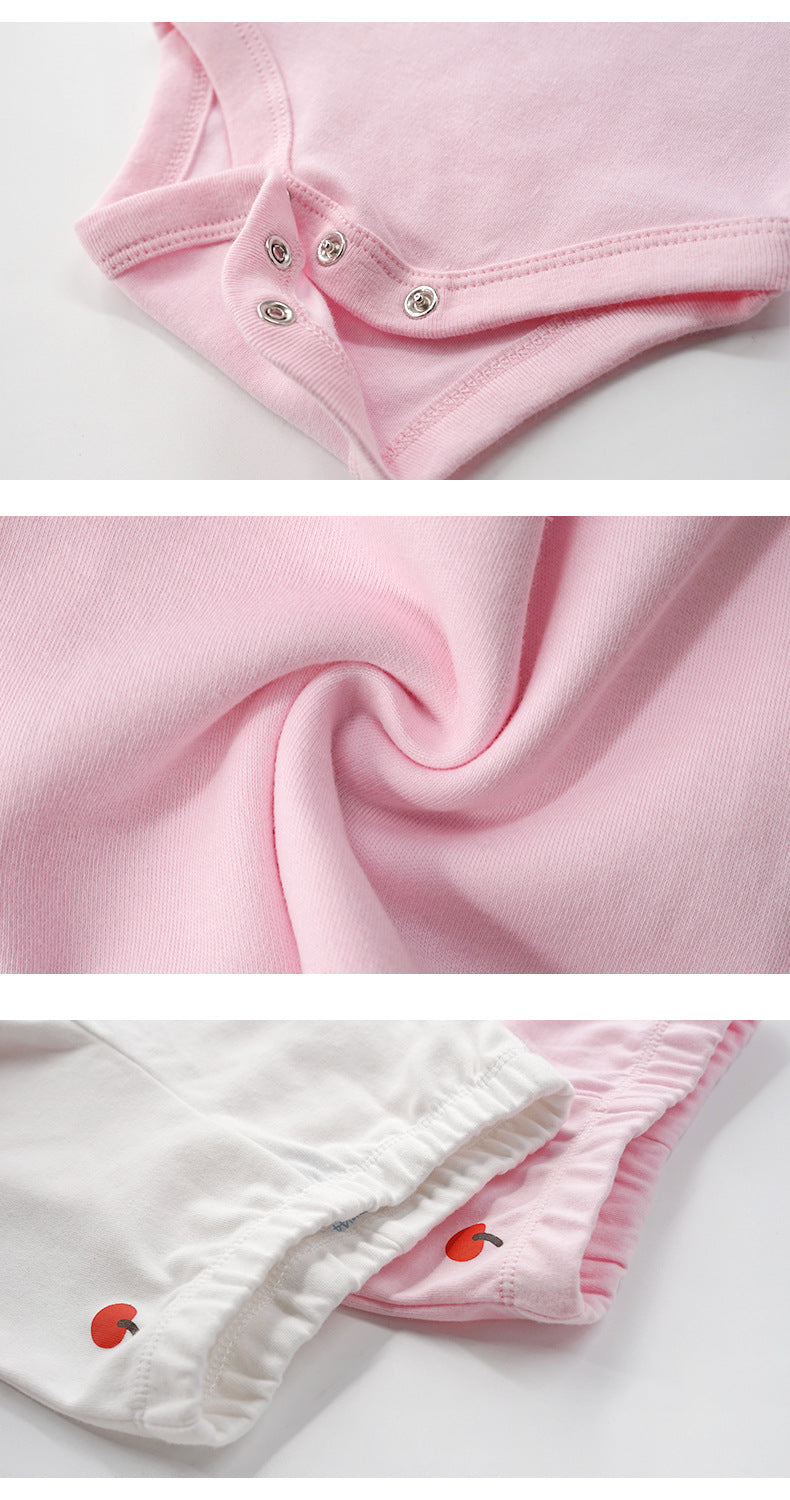 Close-up of soft pink cotton baby bodysuit snaps, fabric texture, and white/pink bottoms with apple embroidery.