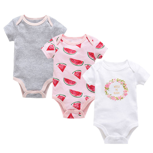 Three soft cotton baby bodysuits: gray, pink with watermelon print, and white with a floral "Watch Me Bloom" graphic.
