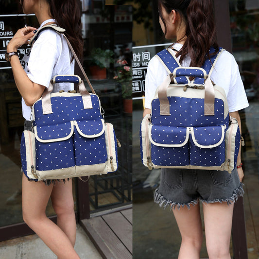 Blue polka dot diaper backpack with beige trim, worn as a shoulder bag and backpack.