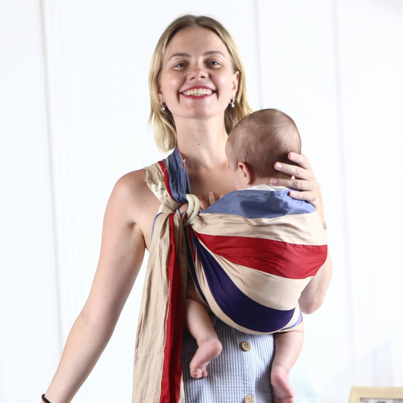 Smiling woman wearing a soft, breathable cotton baby sling in red, blue, and beige stripes, holding a baby.