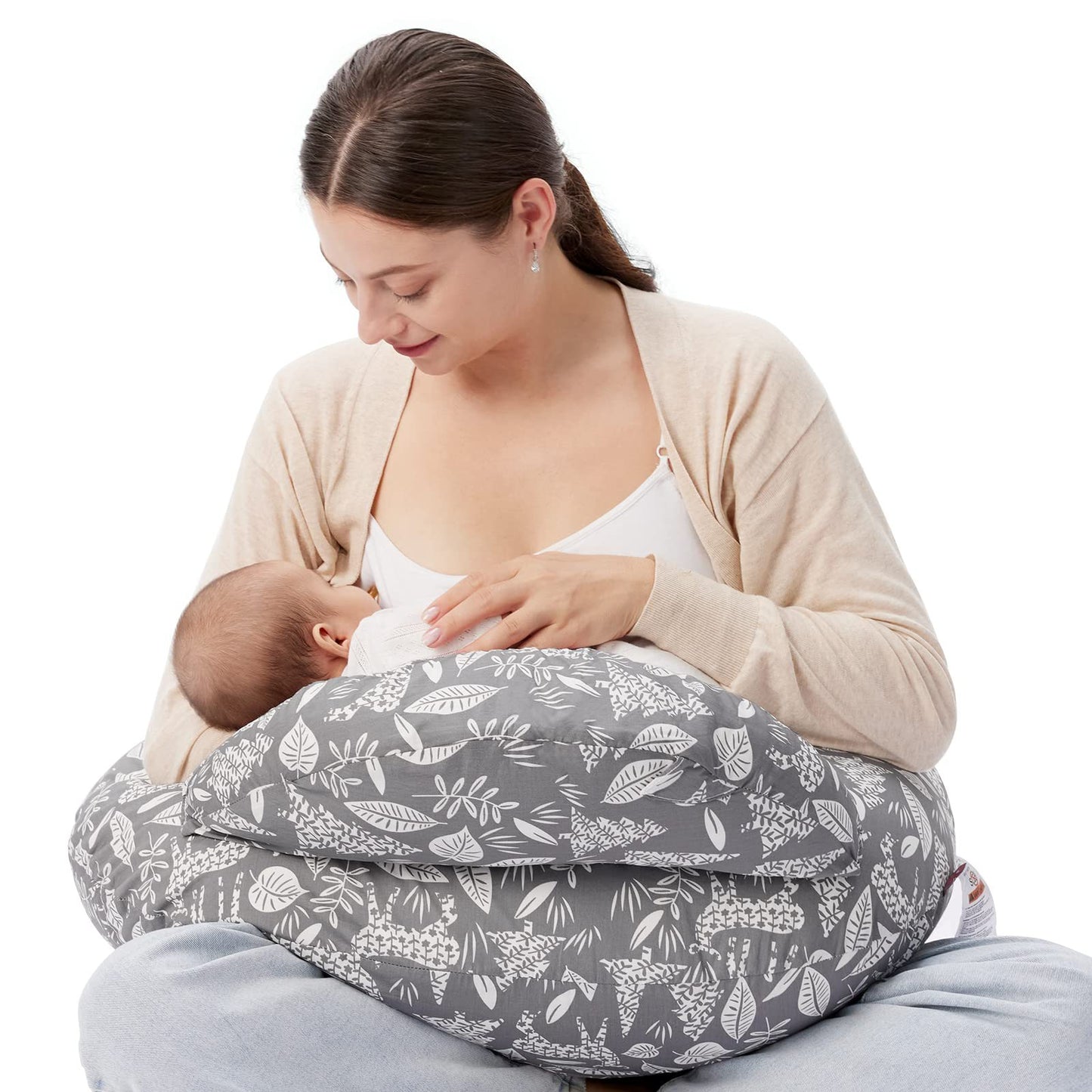 Woman breastfeeding baby using a gray multi-functional nursing pillow with white leaf and llama patterns.