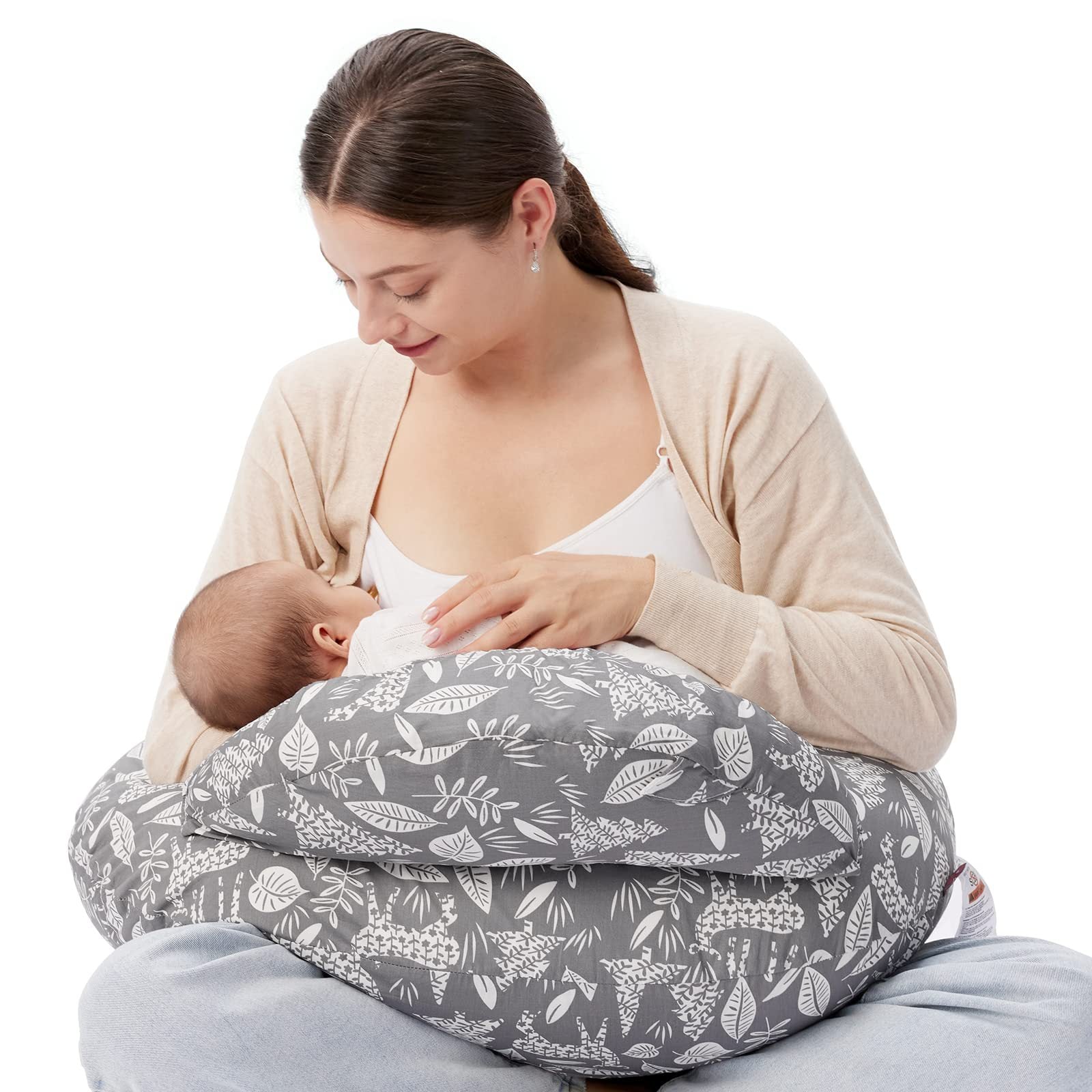 Woman breastfeeding baby using a gray multi-functional nursing pillow with white leaf and llama patterns.