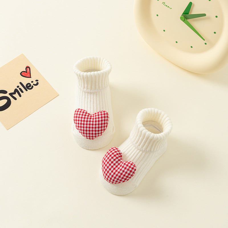 White ribbed cotton baby socks with red and white checkered heart appliqués and anti-slip soles.
