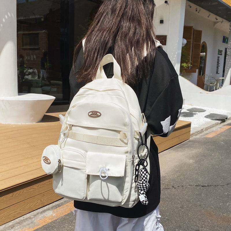 White nylon student backpack with multiple pockets, laptop compartment, and small attached pouch.