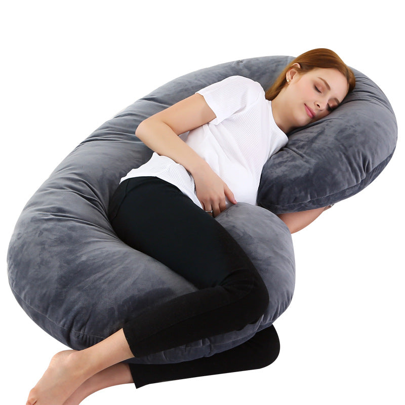 Woman sleeping comfortably on a large gray C-shaped velvet pregnancy pillow.