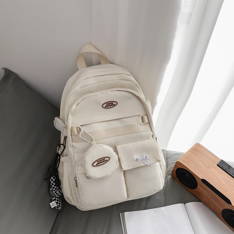 Cream nylon student backpack with laptop compartment, multiple pockets, and a small matching pouch.