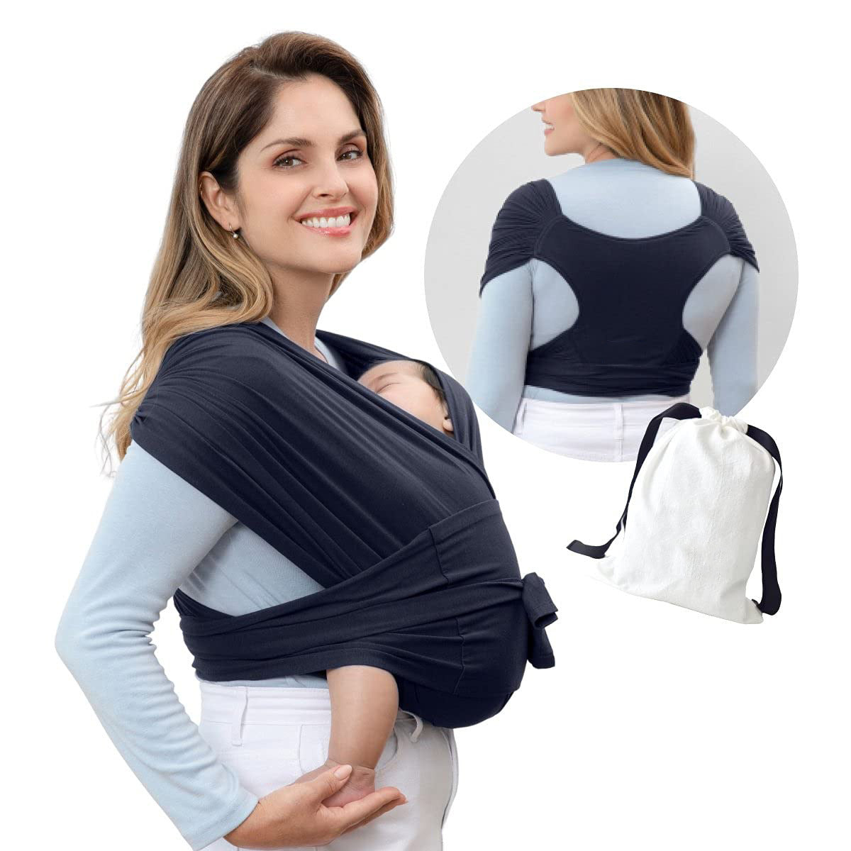 Smiling woman wearing a navy blue ergonomic X-type cotton baby carrier with a sleeping infant, plus a storage bag.