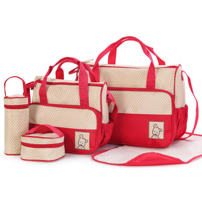 5-piece beige and red polka dot diaper bag set with bear patches, including large bag, small bag, bottle holder, and changing mat.