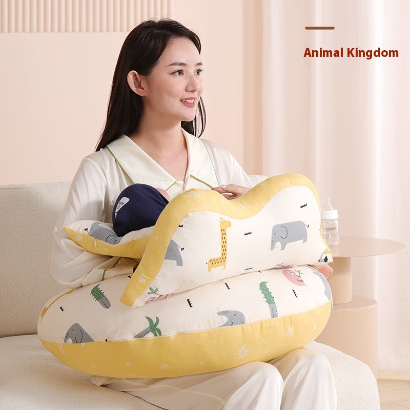 Woman holding a baby on a yellow and white nursing pillow with animal prints.