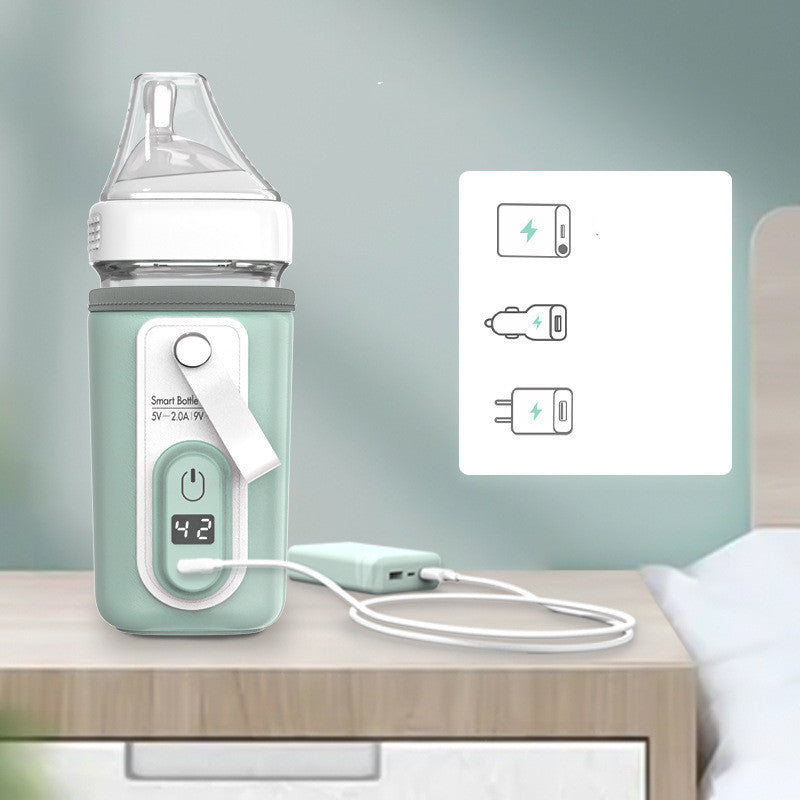 Portable mint green USB bottle warmer with digital display, charging from a power bank on a nightstand.