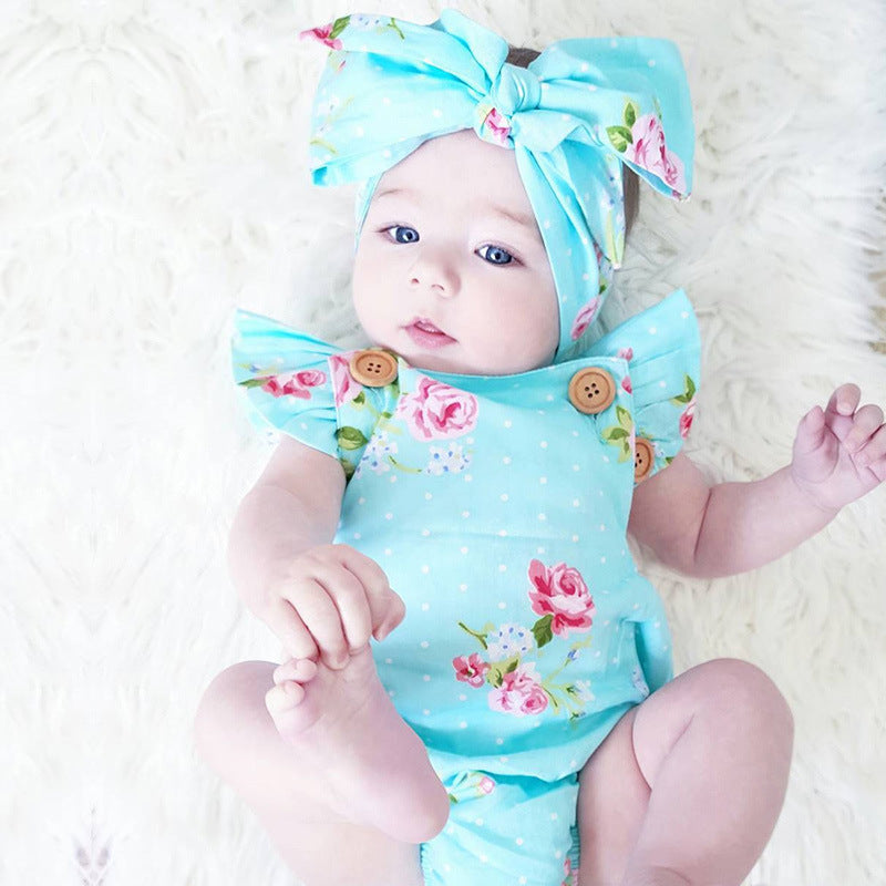Baby girl in a light blue sleeveless chiffon romper with pink floral print, white polka dots, and a matching bow headband.
