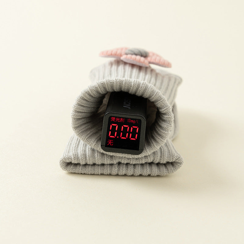 Gray ribbed cotton baby socks with a pink bow accent and a digital display showing "0.00".