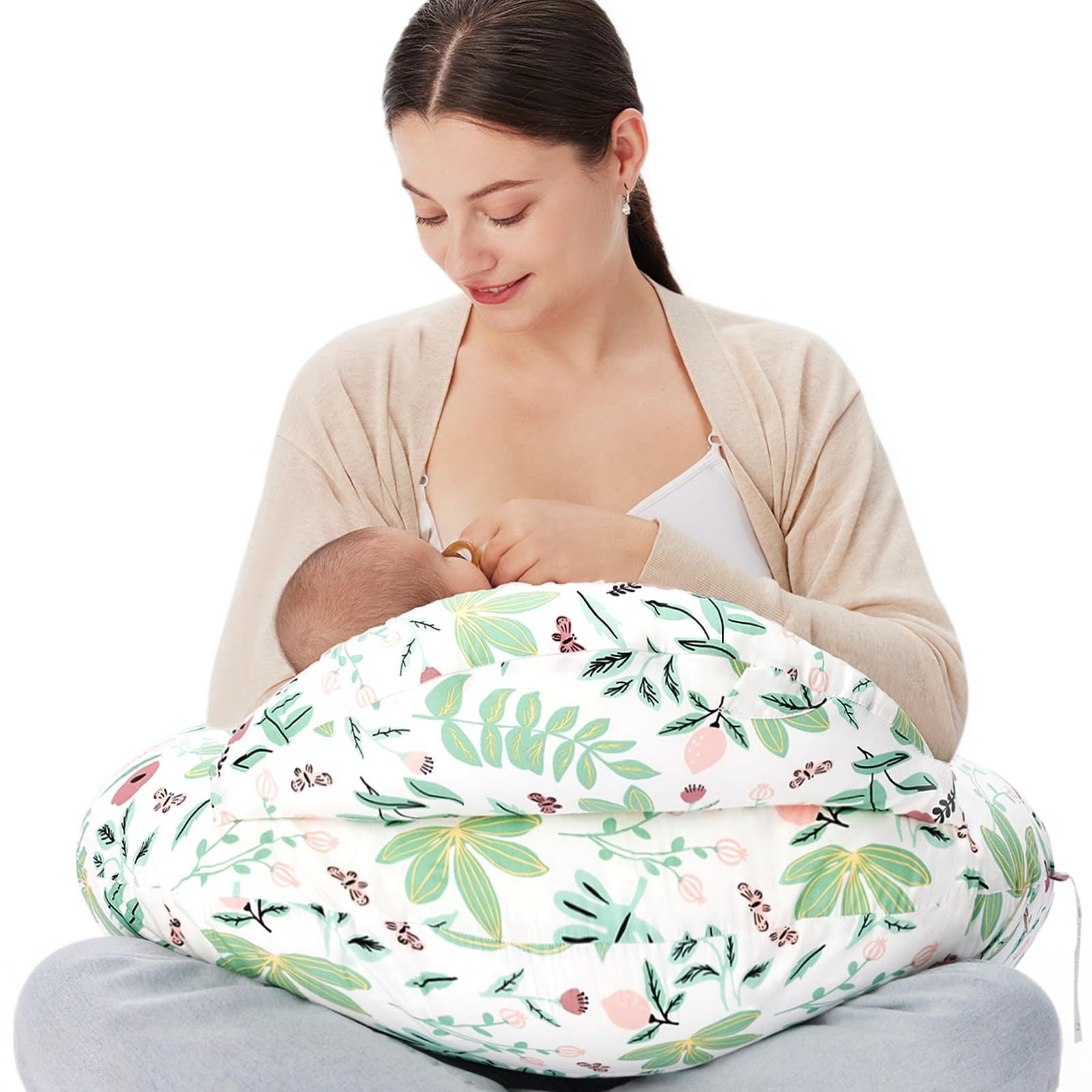 Mother breastfeeding baby using a white nursing pillow with green and pink floral print.