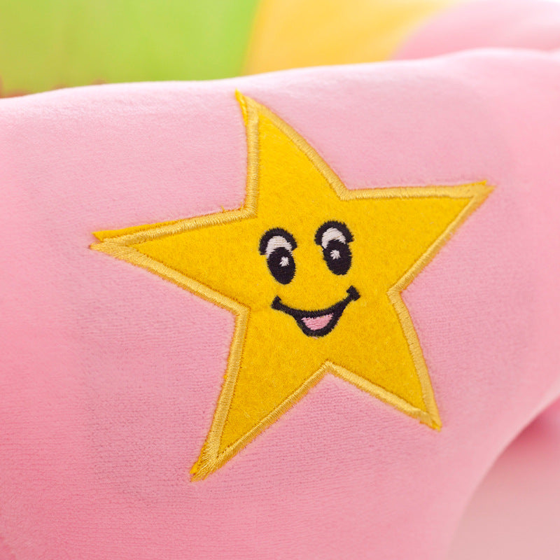 Close-up of a pink plush baby support seat with a yellow embroidered star featuring a smiling face.
