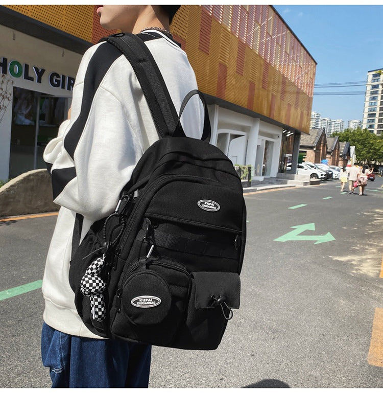Black nylon student backpack with laptop compartment, multiple pockets, and checkerboard charm.