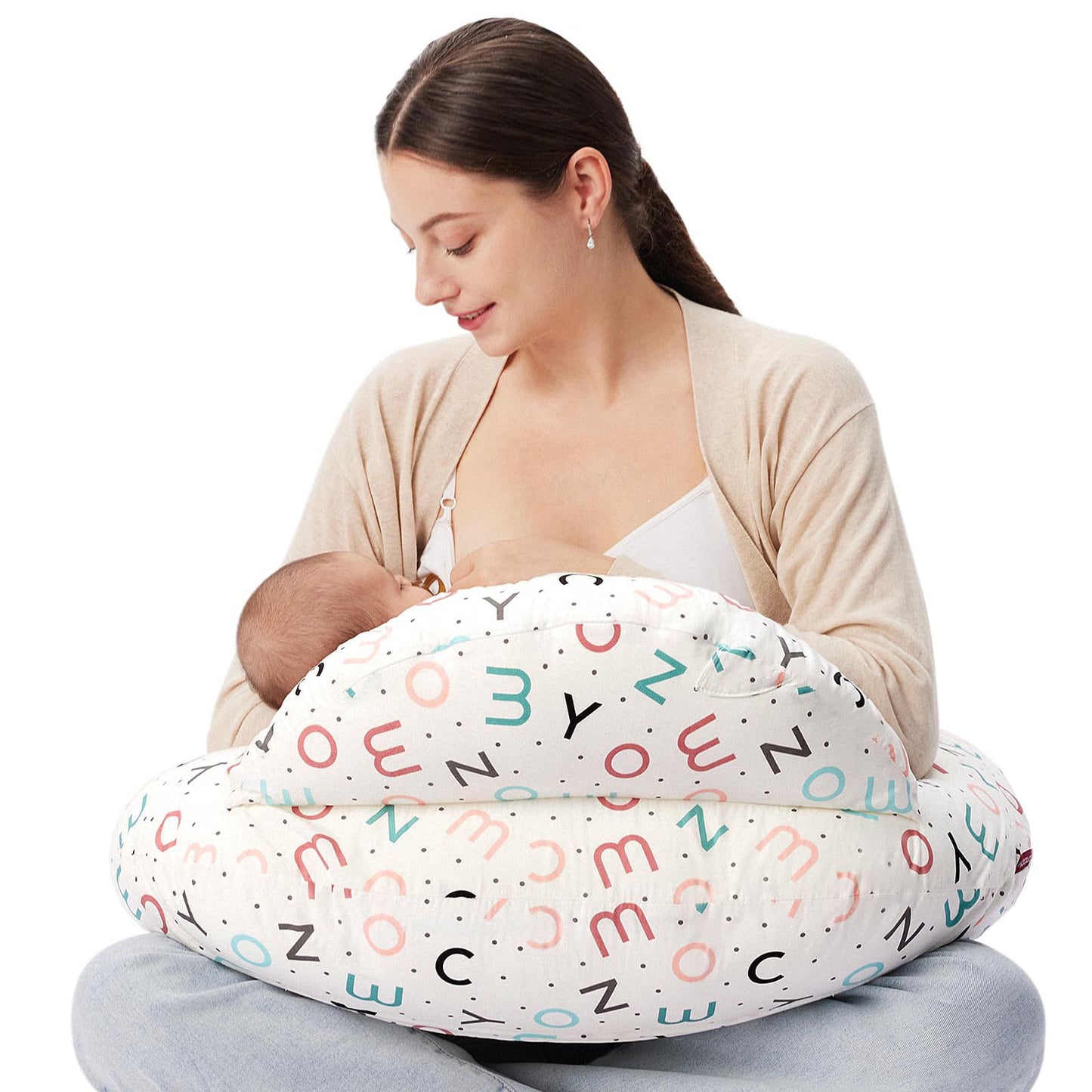 Woman breastfeeding baby with a white multi-use nursing pillow featuring colorful alphabet and dot patterns.