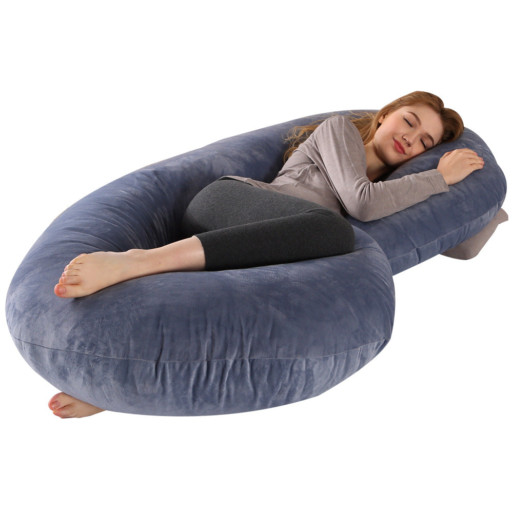 Woman sleeping peacefully on a large, soft blue C-shaped velvet pregnancy pillow.
