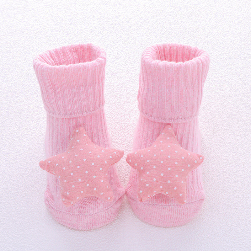 Pink cotton baby socks with white polka dot star embellishments and non-slip soles.